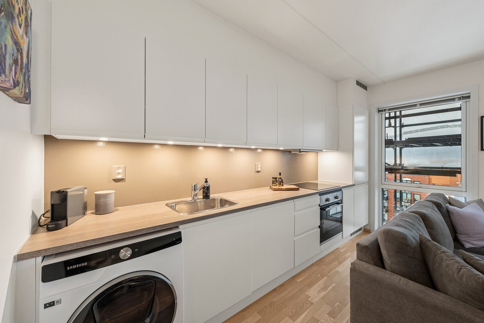 Pen HTH-kjøkkeninnredning med glatte fronter og en benkeplate i laminat med en nedfelt oppvaskkum i stål. Galleribilde