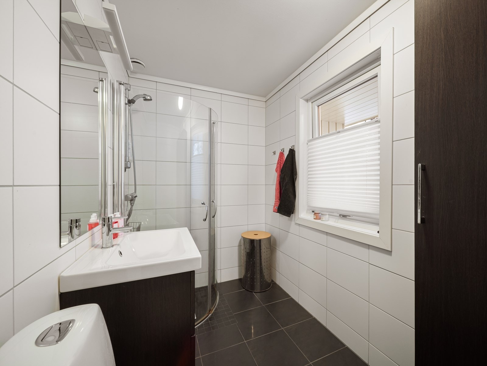 Helfliset bad innredet med baderomsrinnredning med servant, toalett og dusj. Galleribilde