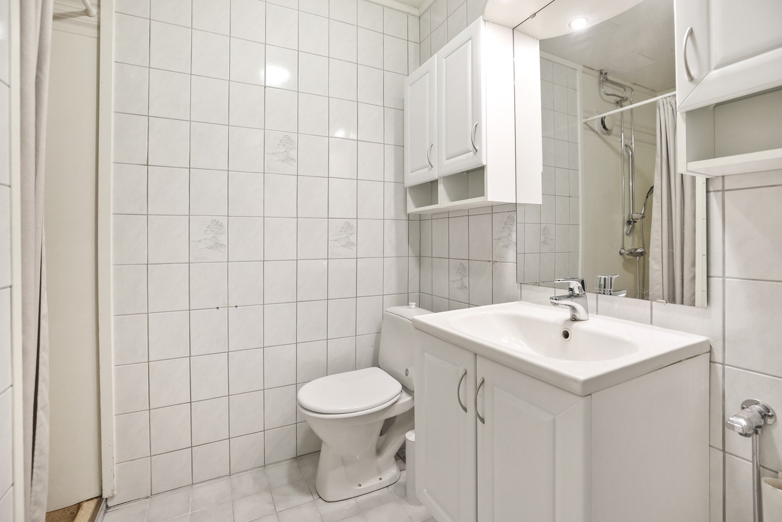 Baderommet har servantinnredning med speil med overlys, gulvstående toalett og dusjhjørne. Galleribilde