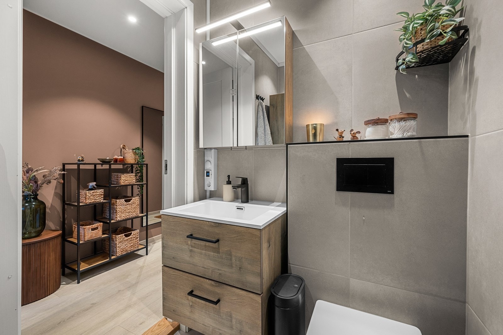 Badet er utstyrt med dusjhjørne med innfellbare dusjdører, servantskap med nedfelt servant og veggmontert toalett. Galleribilde