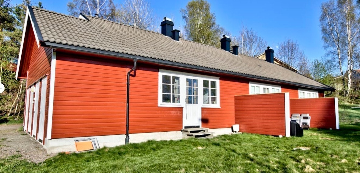 Fra hagesiden, leilighet i midten, med utgang til liten hageflekk med levegg på begge sider. Galleribilde