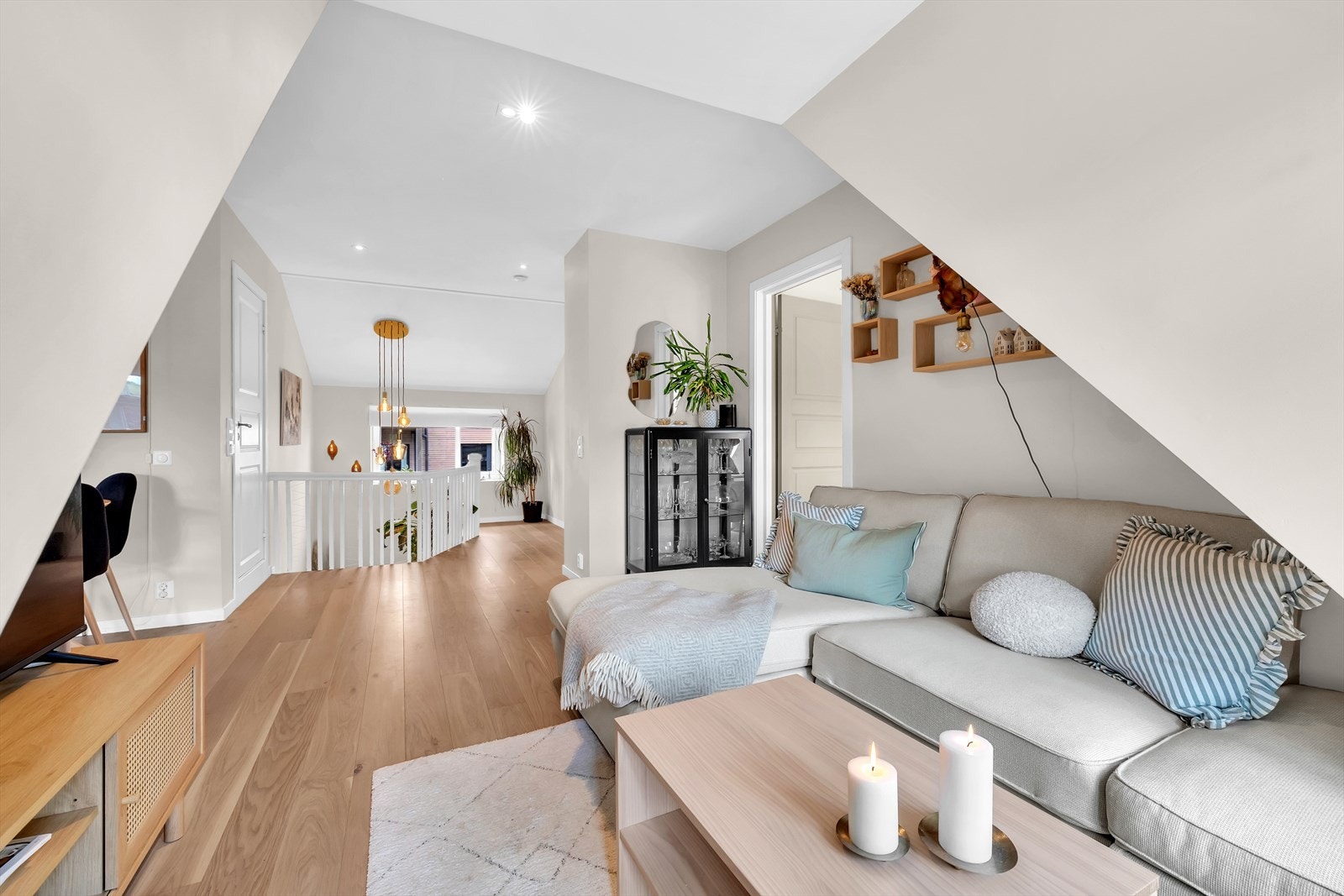 Stuen er gjennomgående med parkettgulv og malte overflater i lyse toner. Trappen binder etasjene sammen og slipper inn lys gjennom det store vinduet i enden av gangen. Galleribilde