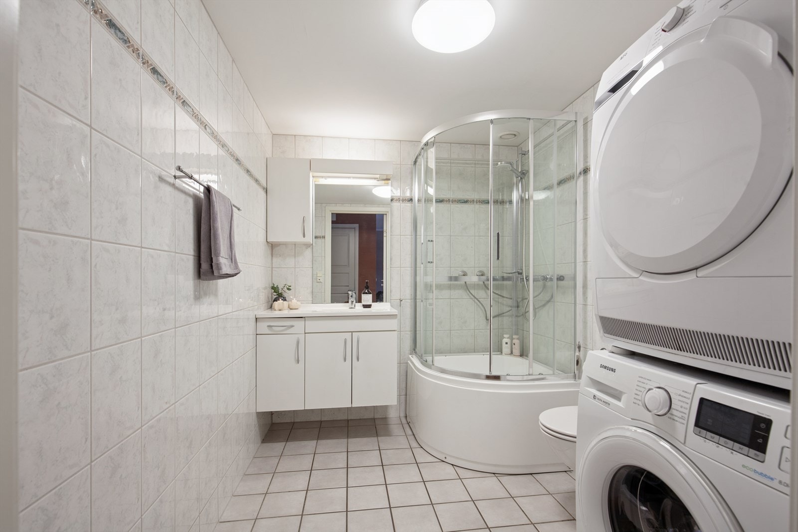 Flislagt baderom med plass til vaskemaskin og tørketrommel. Galleribilde