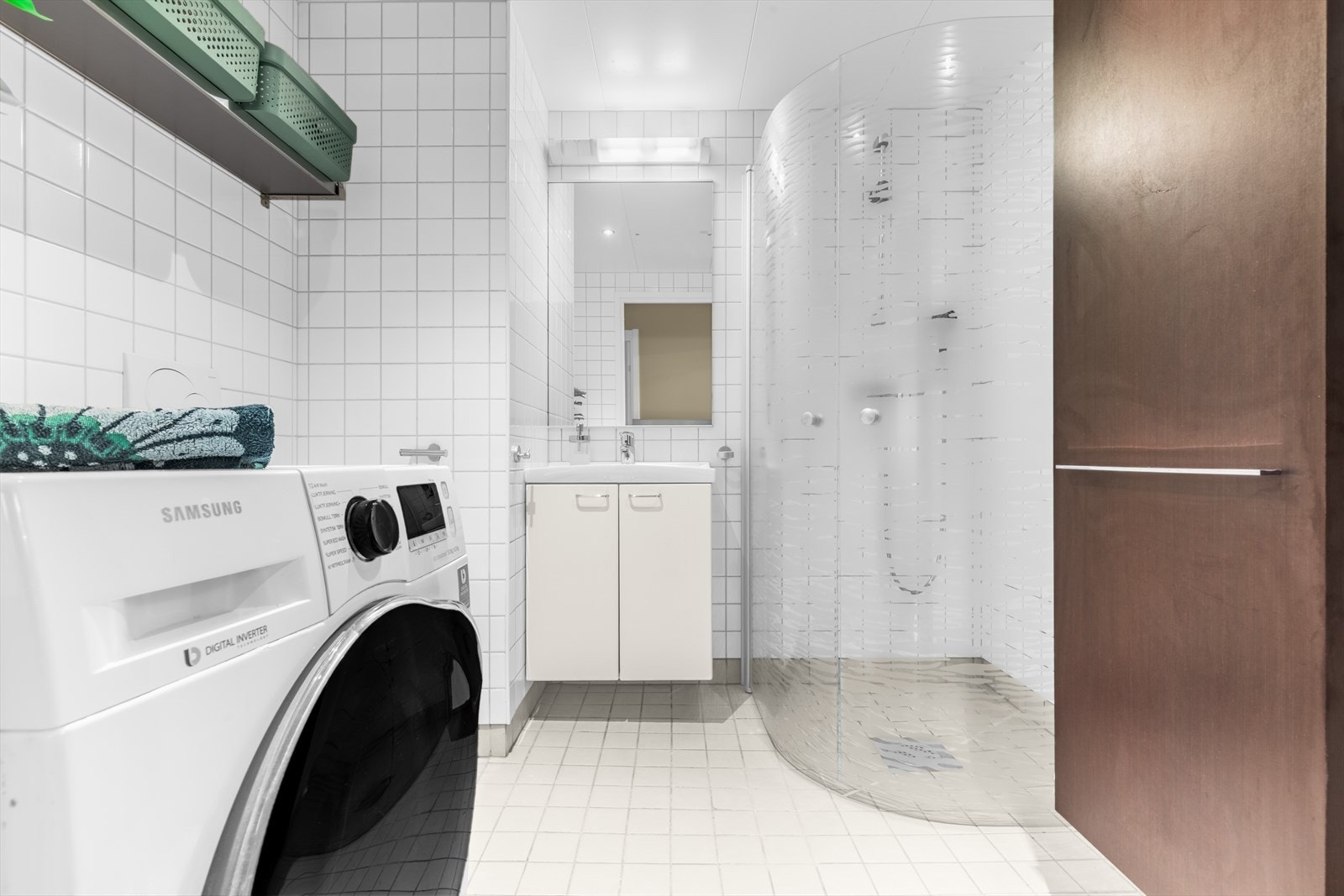 Badet er innredet med heldekkende servant med servantskap, speil, høyskap, veggmontert WC og to svingbare dusjvegger. Galleribilde