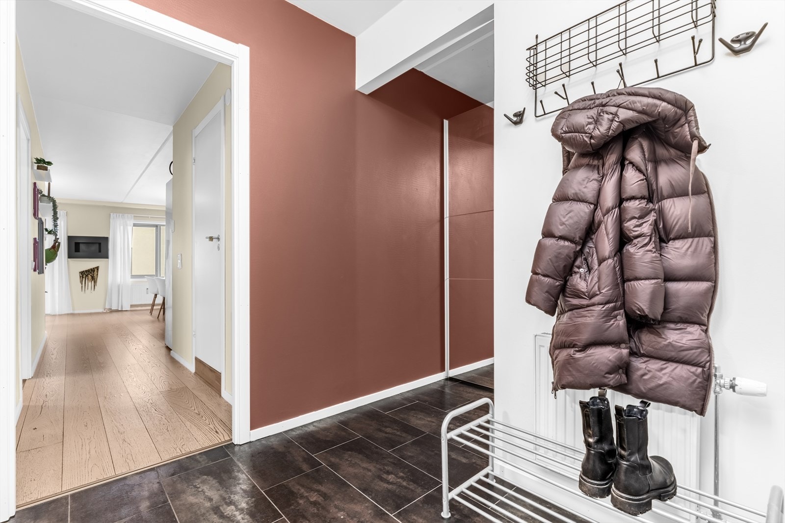 Velkommen inn i en romslig og innbydende entré som gir et godt førsteinntrykk av boligen. Her er det god plass til både knaggrekke, skohylle og skoskap. Galleribilde