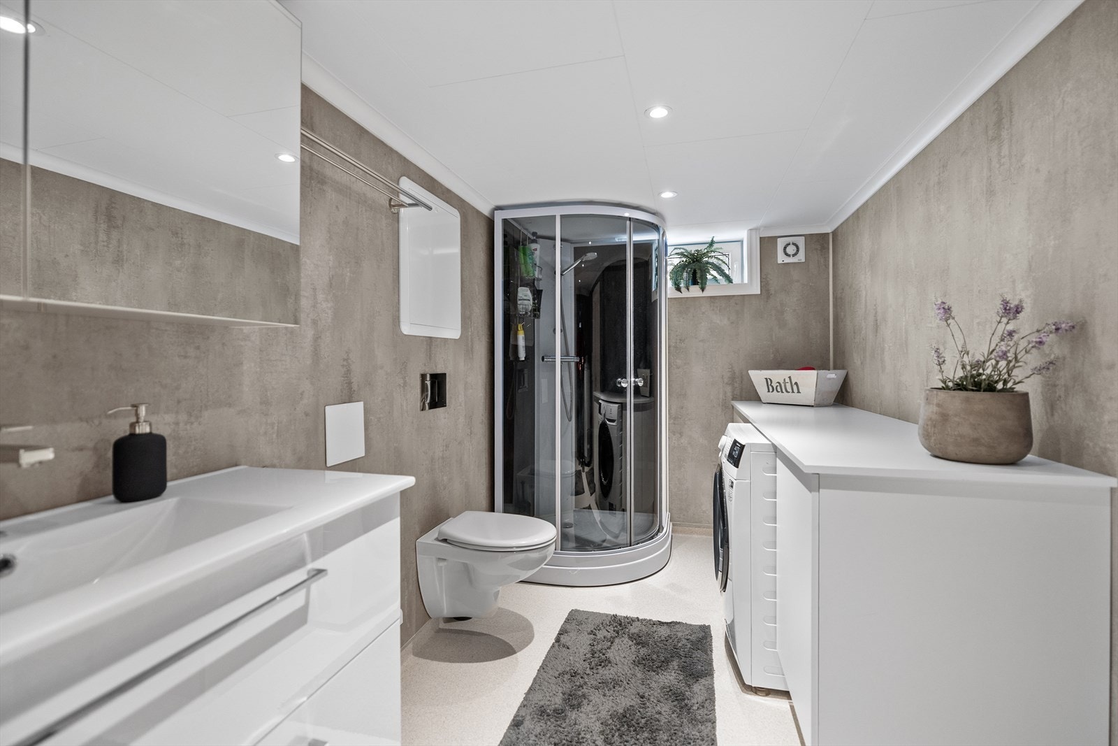 Dusjkabinett og opplegg for vaskemaskin gir praktisk bruk i kjellerbadet. Galleribilde