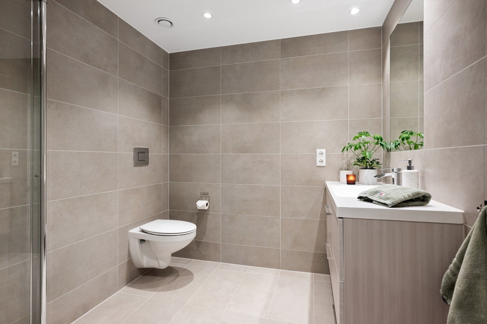 Det private badet er stilrent innredet med flislagte overflater og vegghengt toalett. Galleribilde