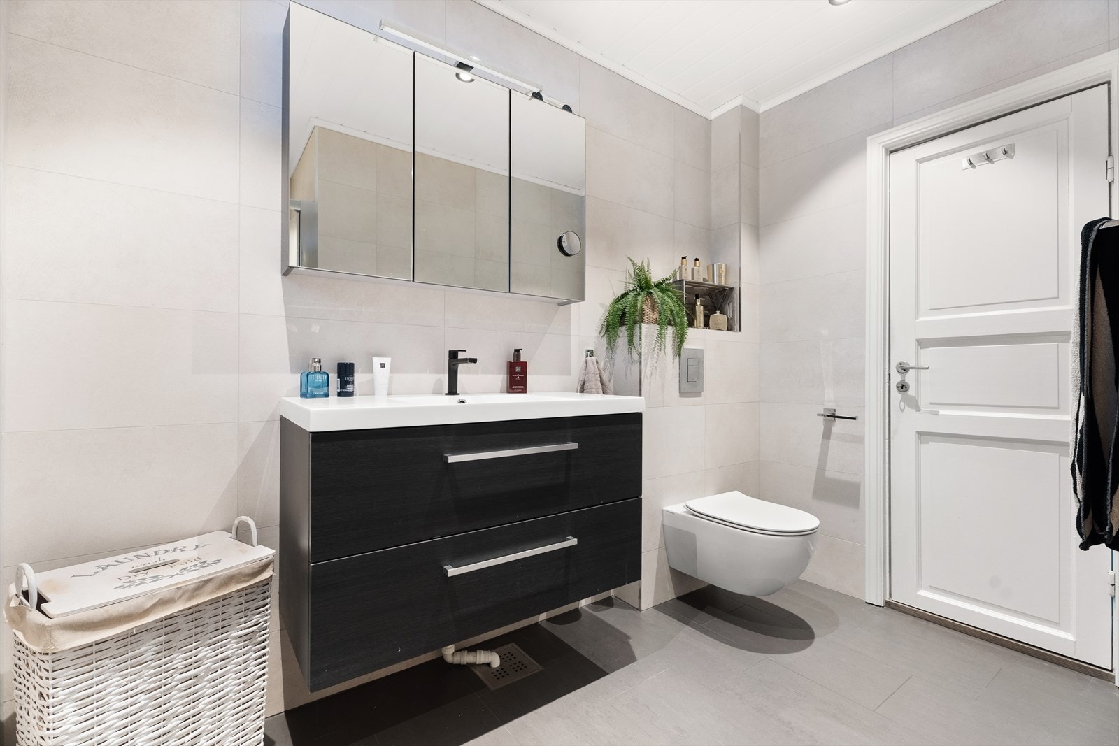 Baderomsinnredning med heldekkende servant, skuffer og et stort speilskap med belysning. Galleribilde