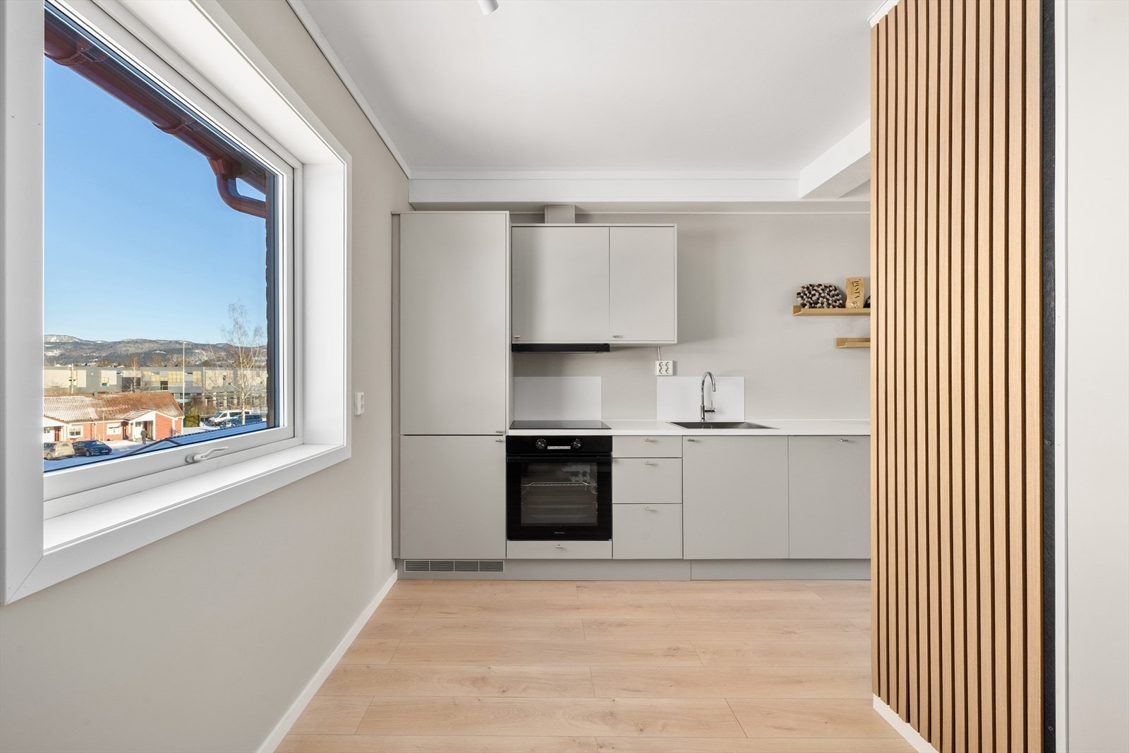 Hvit benkeplate i laminat med nedfelt platetopp og oppvaskkum i rustfritt stål. Fuktbestandige plater på vegg ved platetopp og oppvaskkum. Galleribilde