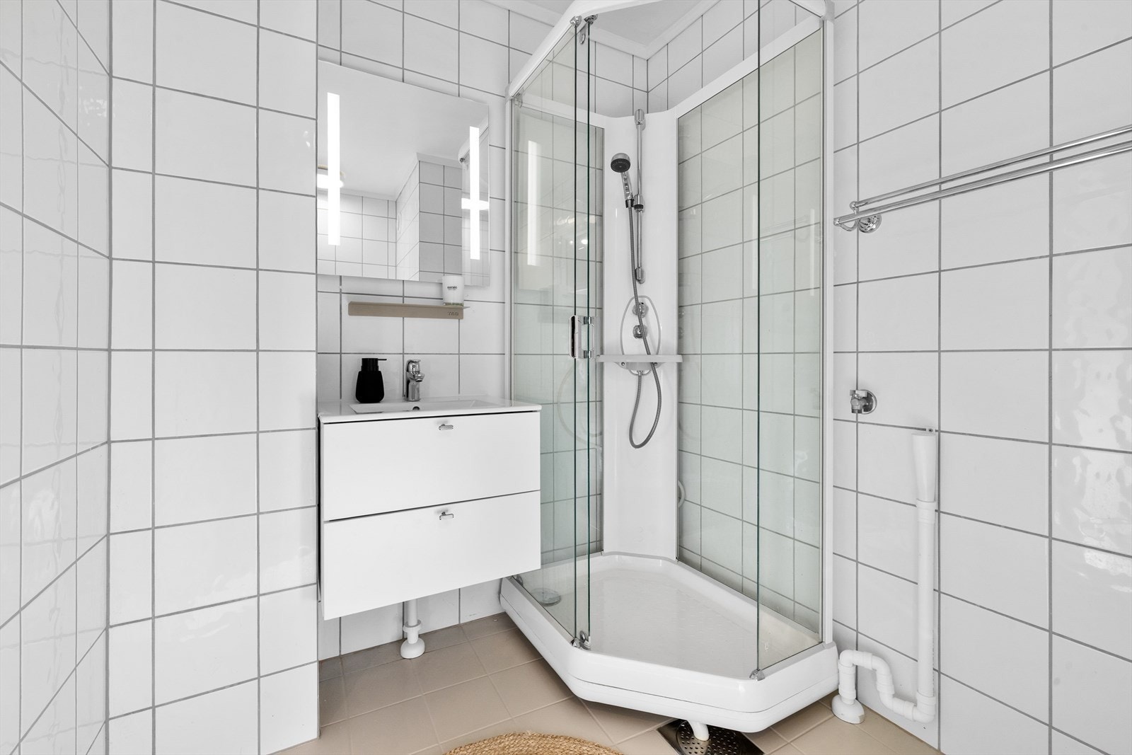 Lyst, flislagt bad fra ca. 2003. Badet er utstyrt med elektriske varmekabler i gulv, gulvmontert toalett, dusjkabinett og opplegg for vaskemaskin. Galleribilde