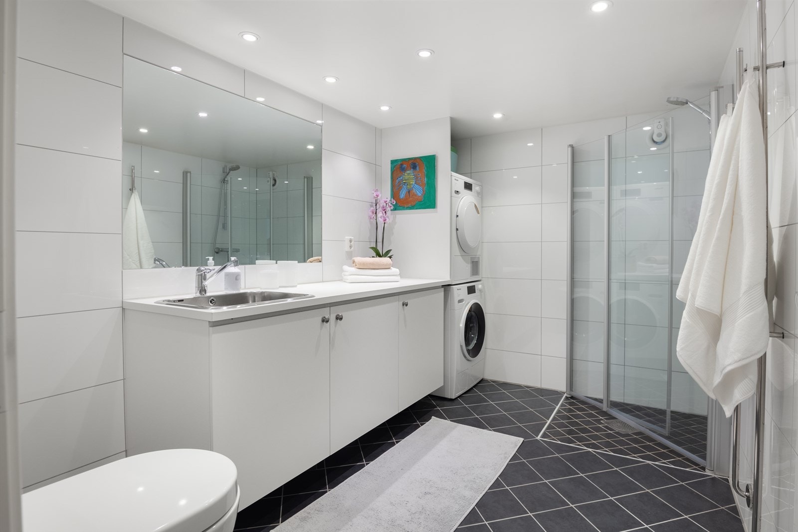 Flislagte overflater med gulvvarme - utstyrt med vaskemaskin og tørketrommel, pent integrert innerst i hjørnet. Galleribilde