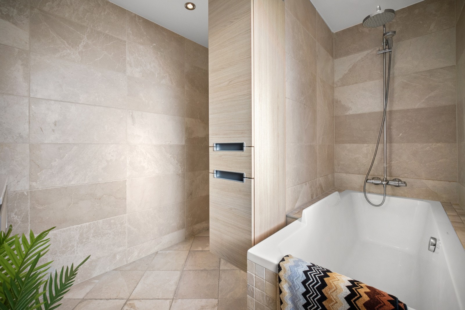 Videre har badet et vegghengt toalett og et badekar i nisje med regnfallsdusj. Galleribilde