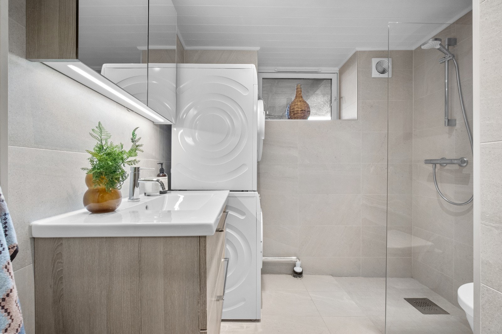 Badet i kjelleren er delikat og moderne, med lyse fliser på veggene. Badet ble pusset opp i 2015. Galleribilde