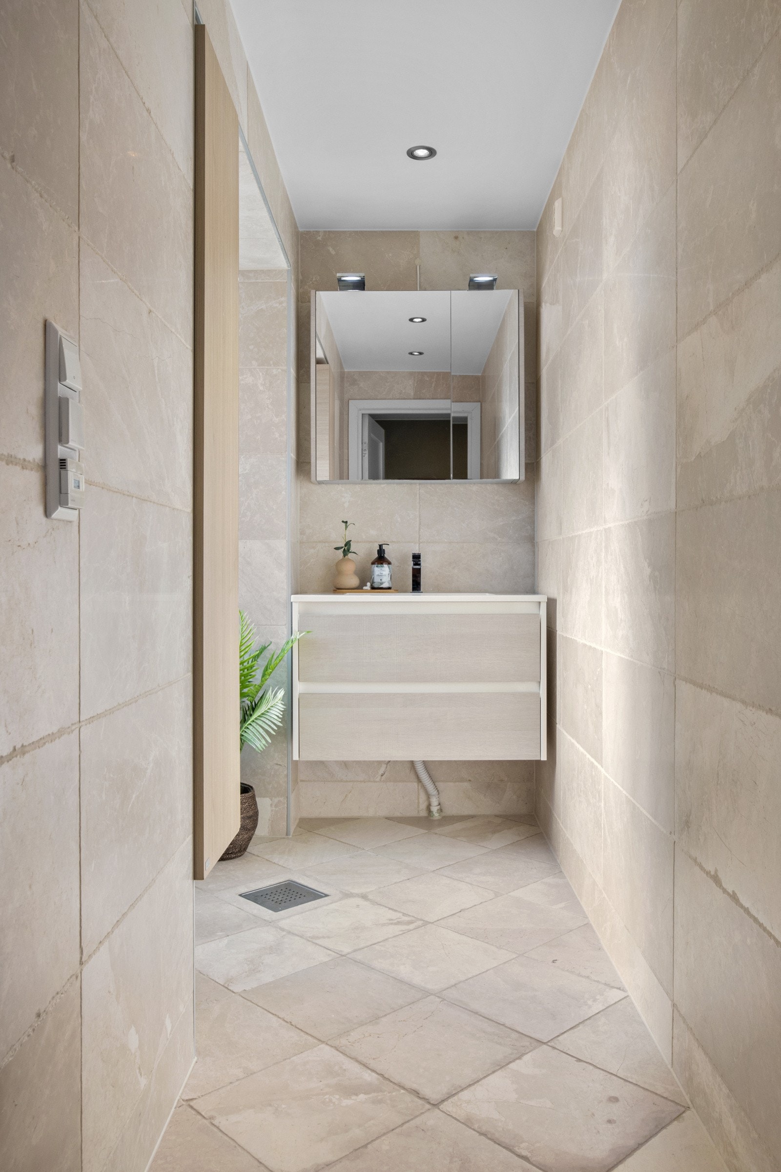 Baderomsinnredningen har lyse, finerte fronter og består av en heldekkende servant på en skuffeseksjon og et dobbelt speilskap med belysning. Galleribilde