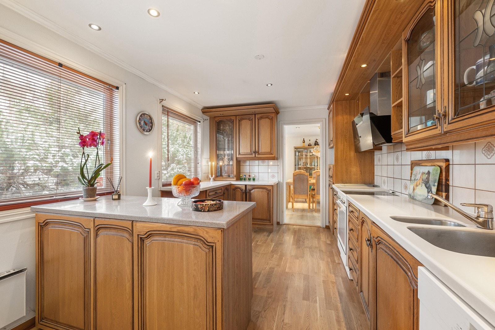 Kjøkkenet er praktisk plassert ved spisestuen og har eldre innredning med profilerte fronter, laminat benkeplate, oppvaskkum og fliser over benken. Galleribilde