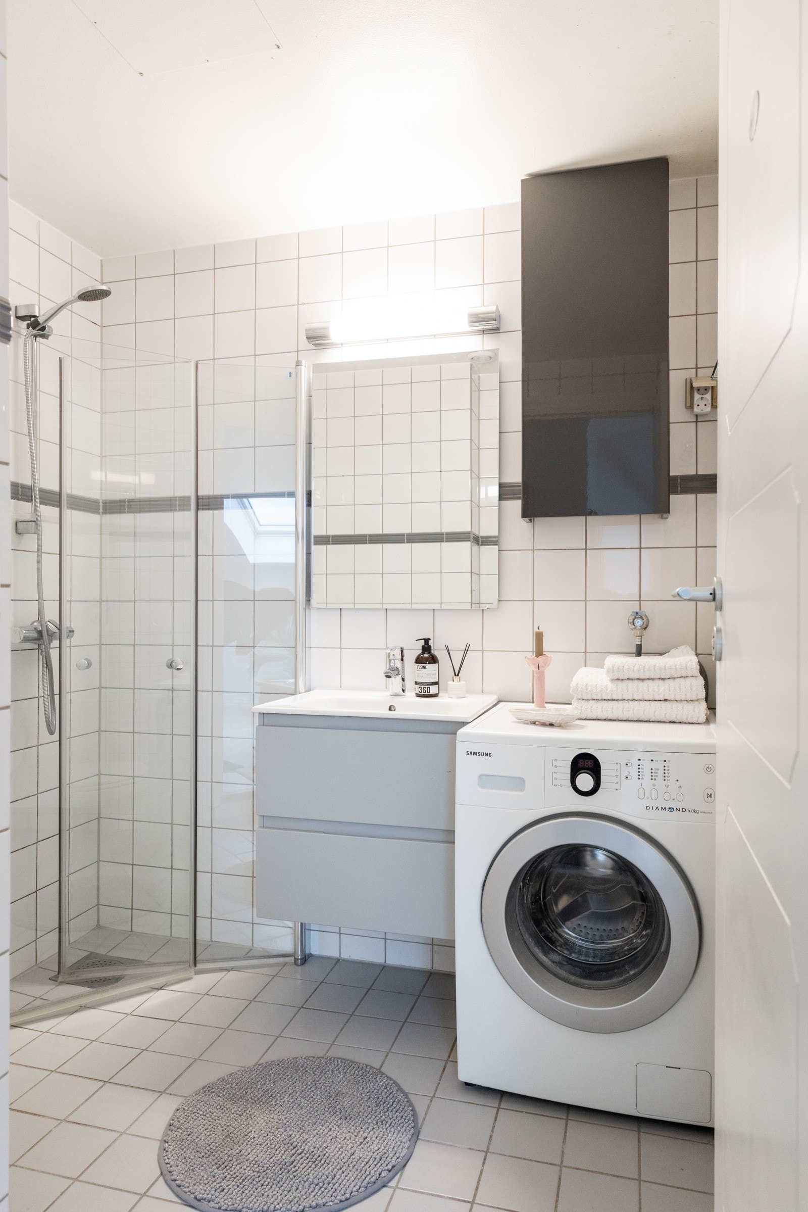 Innredningen på badet består av enkel servant med vegghengt speil, dusjhjørne med svingbare glassdører, WC og opplegg til vaskemaskin Galleribilde