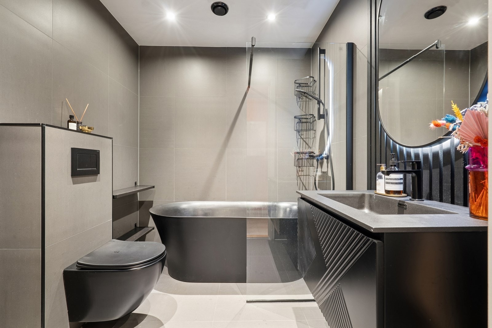 Baderom i 1. etasje med veggmontert toalett, servant med skuffer og speil, samt badekar med dusjnisje. Gulvvarme. Galleribilde