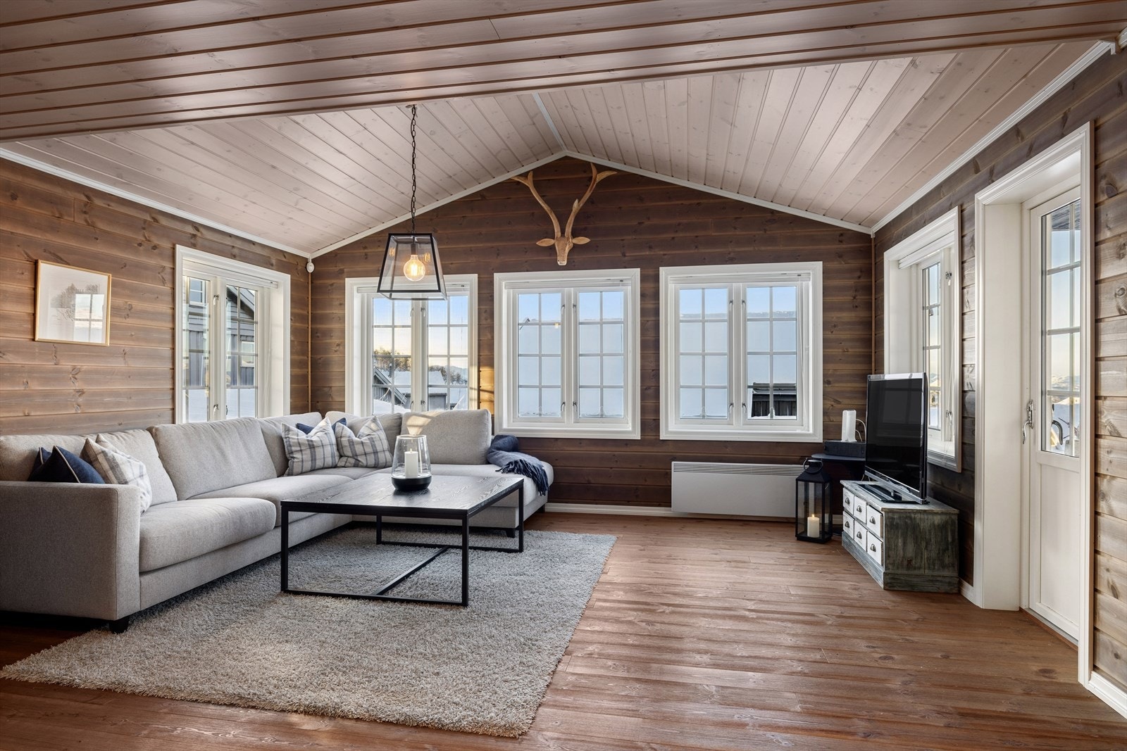 Stuen inviterer til hyttekos i særklasse. Store vindusflater gir lys, utsikt og luft - et rom der naturen utenfor smelter sammen med den lune atmosfæren inne. Her blir både ro, hygge og samvær en daglig opplevelse. Galleribilde