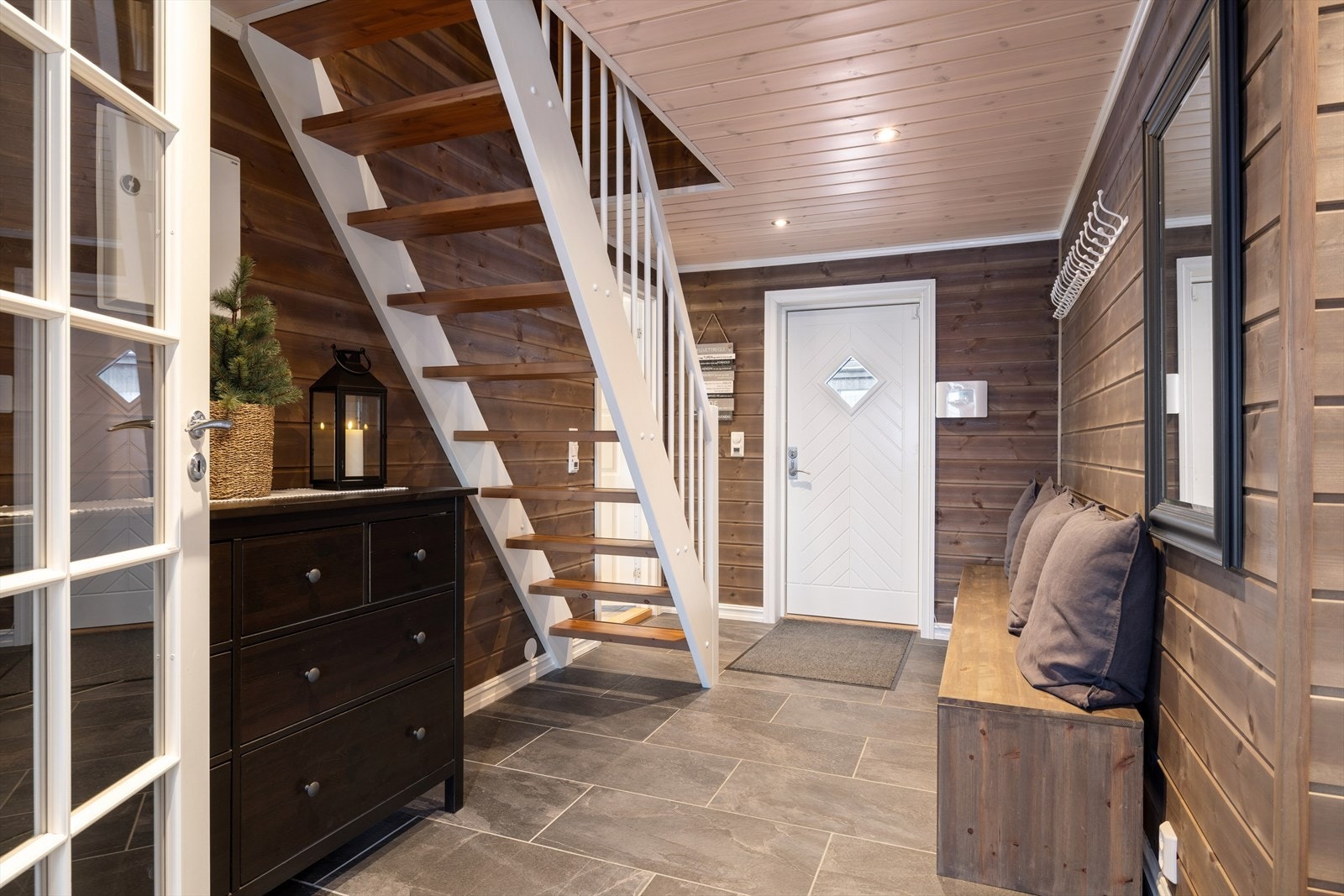 En smart og romslig entré med plass til både yttertøy og sko. Flotte skiferfliser gjør det enkelt å holde orden, samtidig som det tåler både vinterens snø og vårens våte dager. Galleribilde