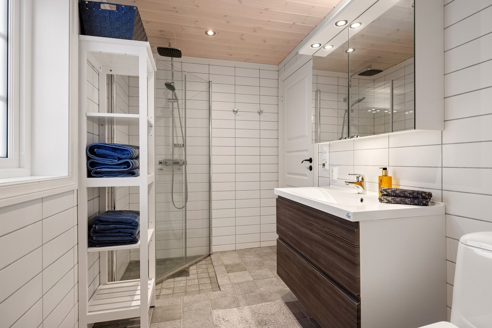 Badet fremstår lyst og innbydende, med god skapplass i innredningen. Speilskap med integrert lys gir praktisk funksjon, og varmekabler i gulvet sørger for ekstra komfort på kalde dager. Galleribilde