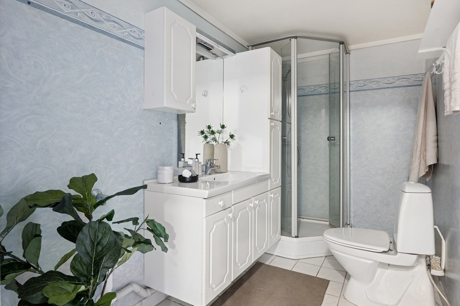 Badet er fra 90-tallet og inneholder innredning, servant, wc, opplegg for vaskemaskin og nyere dusjkabinett. Våtrommet må oppgraderes for å tåle normal bruk etter dagens krav. Galleribilde