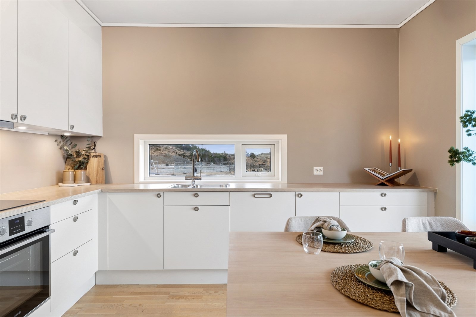 Kjøkkenet er stilrent innredet med hvite, slette fronter og trefarget benkeplate i laminat. Et romslig kjøkken som gir godt med skap- og skuffeplass, samt gode arbeidsflater på benk. Galleribilde