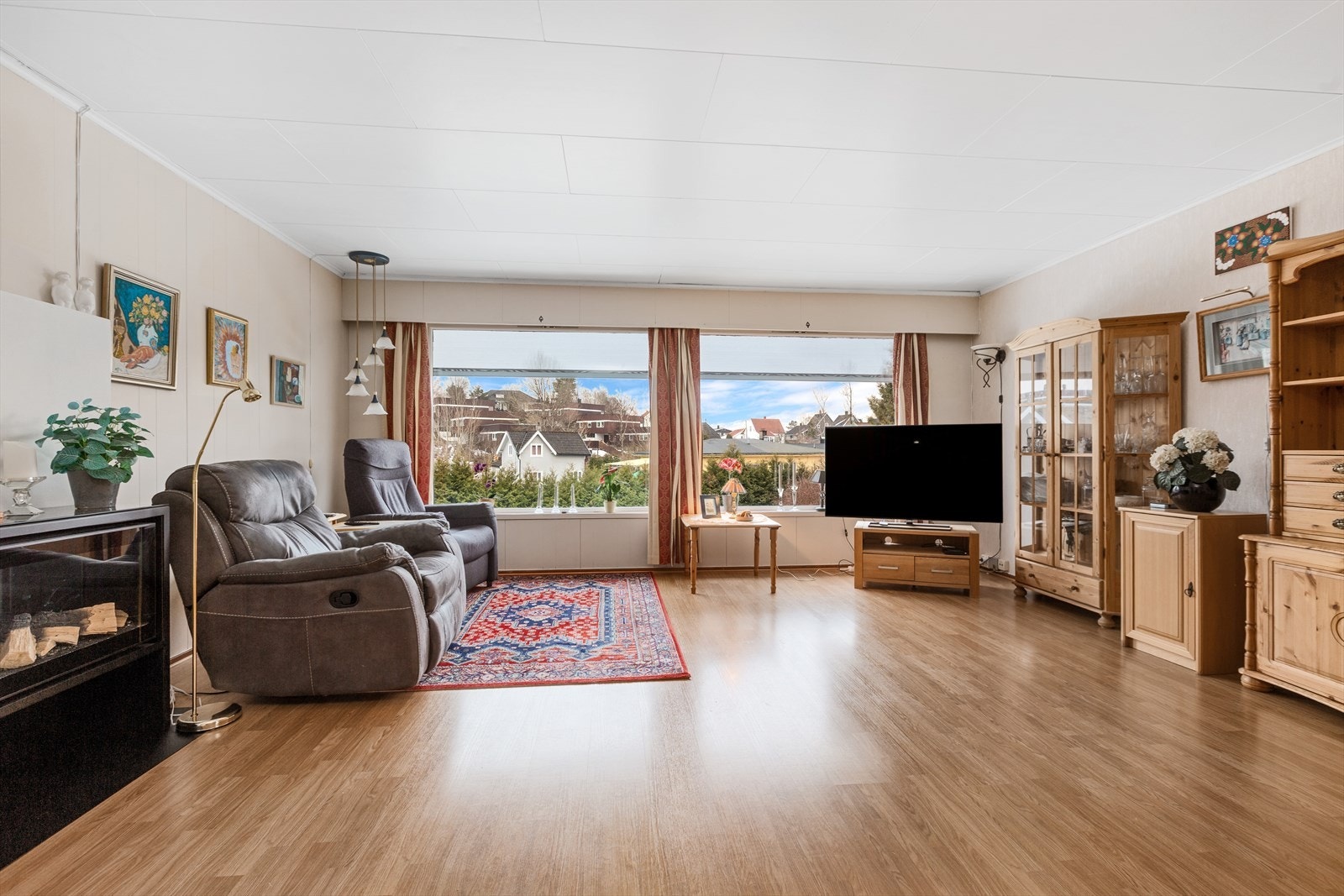 Stue/spisestue med laminat på gulv og tapet/malte plater på vegger. Det ble montert elektriske utvendige screens på 3 av vinduene i 2018 Galleribilde