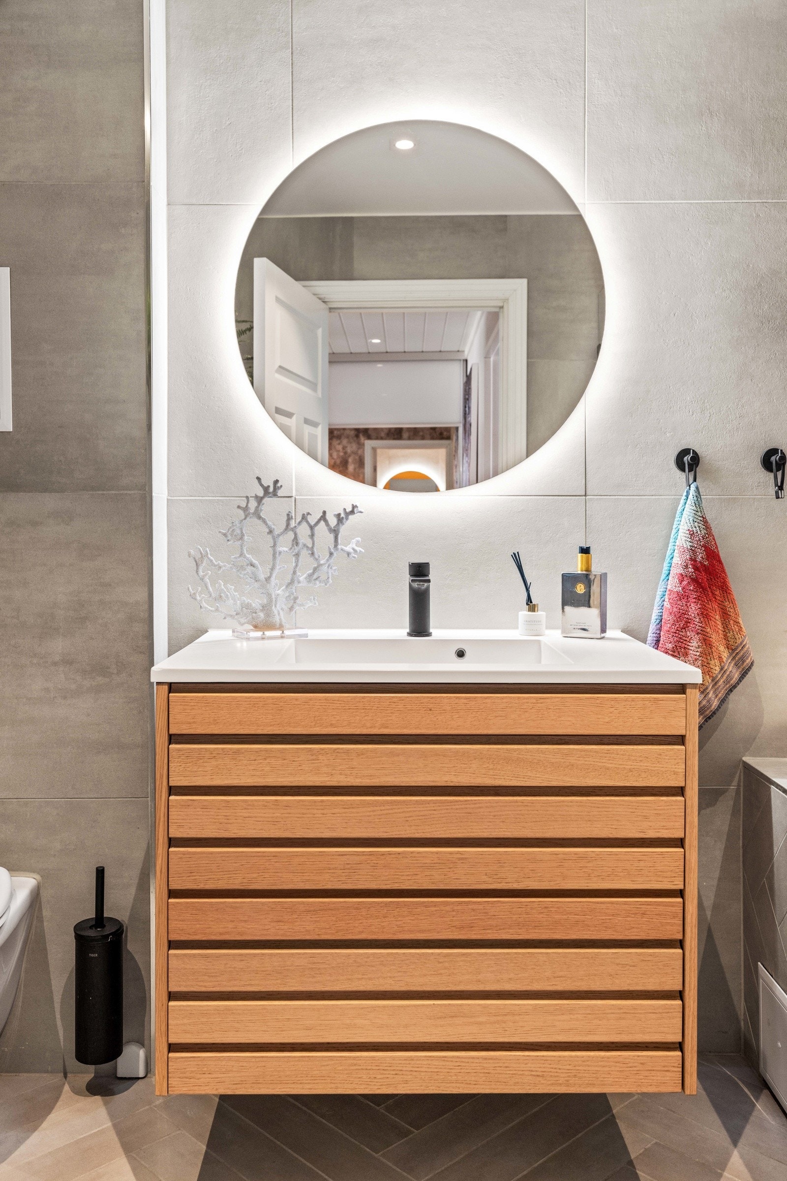 Badet har moderne innredning med speil, veggmontert wc og badekar med dusjgarnityr. Galleribilde