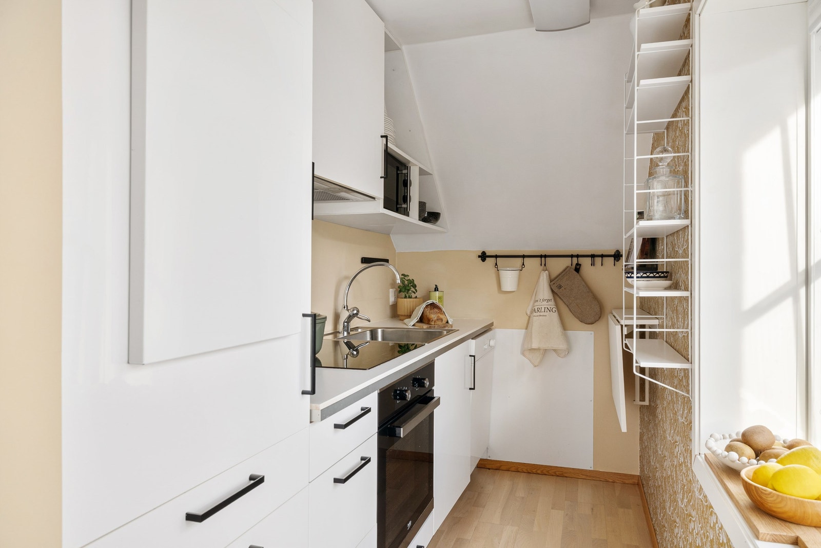 Praktisk kjøkken i hvit utførelse med diverse oppbevaringsløsninger. Galleribilde