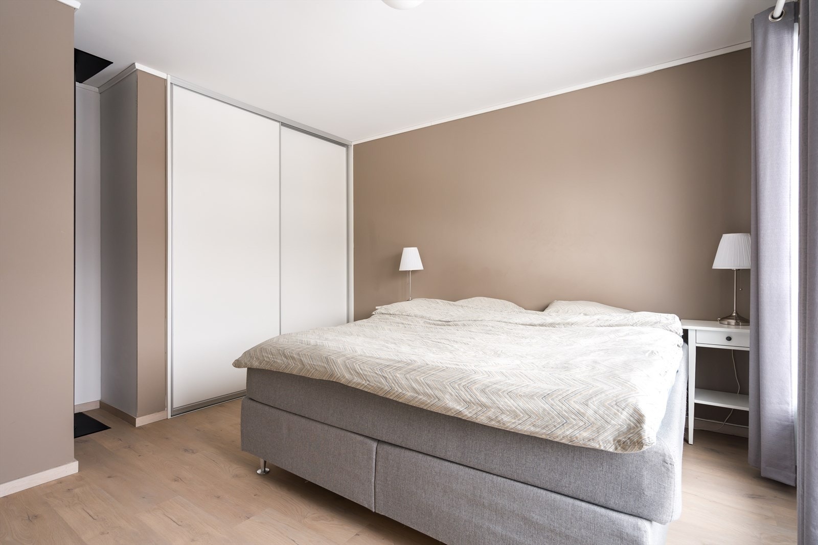 Soverommet har mye oppbevaring i en plassbygd skyvedørsgarderobe med hvite fronter. Galleribilde