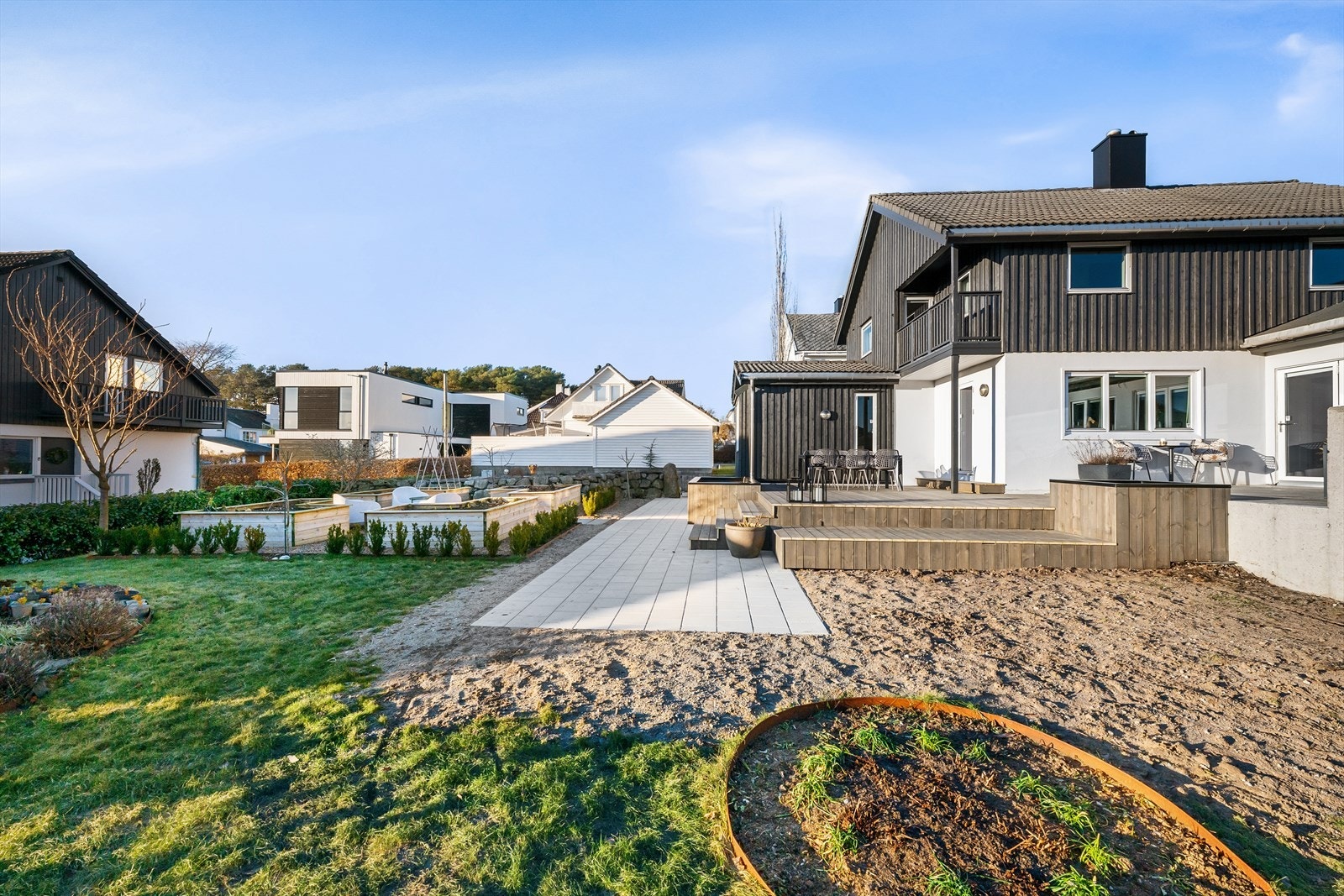 En påkostet og innholdsrik tomt med varierte soner. Her har du boltreplass for lek, egen grønnsakshage omgitt av dansk elvestein og cortenstål, hellegang og stor royal terrasse, samt støpt dekke og grillplass. Galleribilde