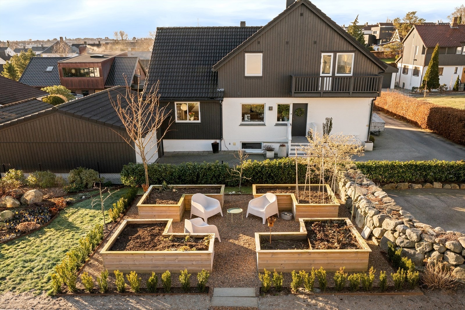 En påkostet og innholdsrik tomt med varierte soner. Her har du boltreplass for lek, egen grønnsakshage omgitt av dansk elvestein og cortenstål, hellegang og stor royal terrasse, samt støpt dekke og grillplass. Galleribilde