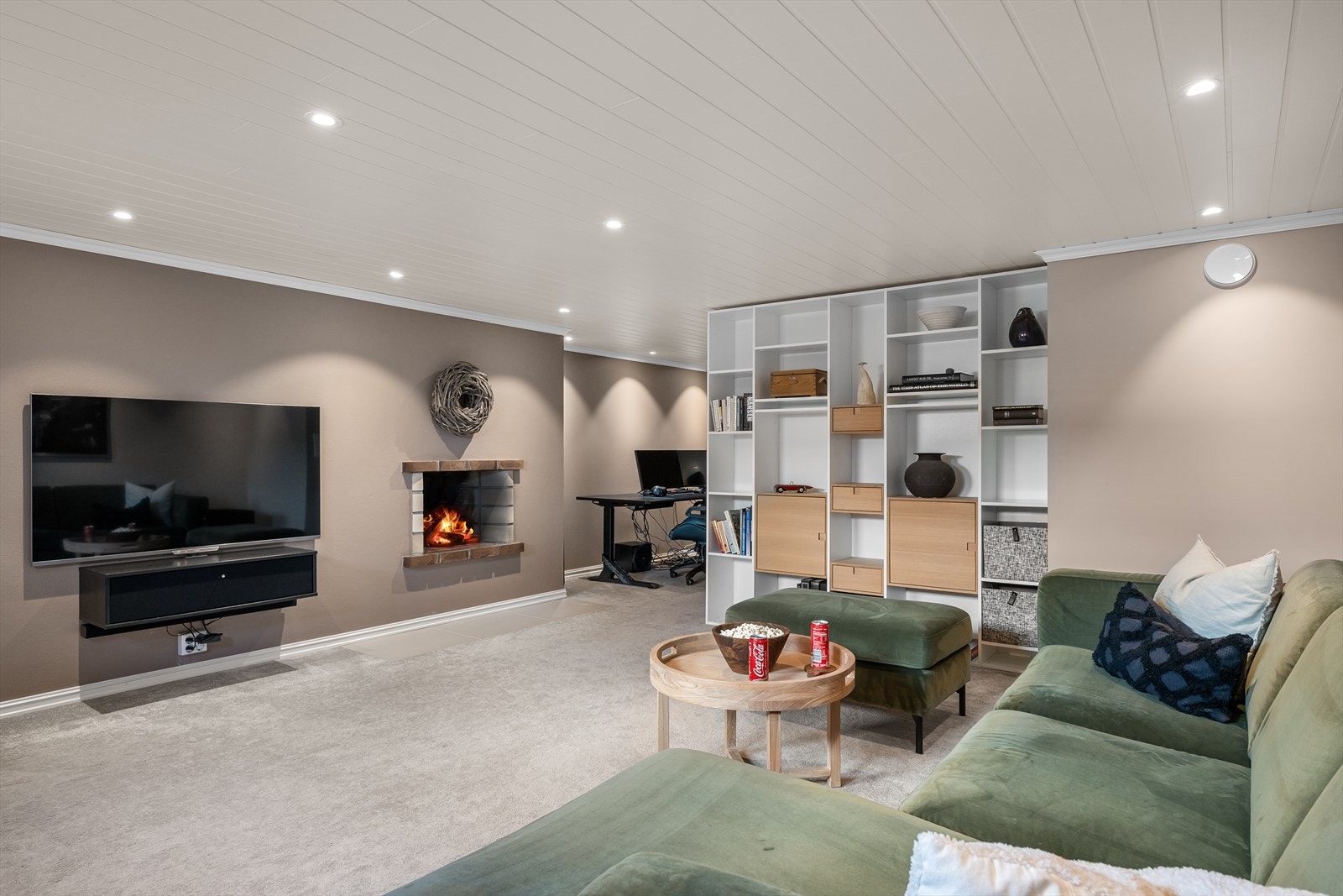 Stor kjellerstue med lunt, moderne teppe og peis/grue for ekstra kos. Avdelt med bokhylle for egen sone til gaming og poker/spill. Galleribilde