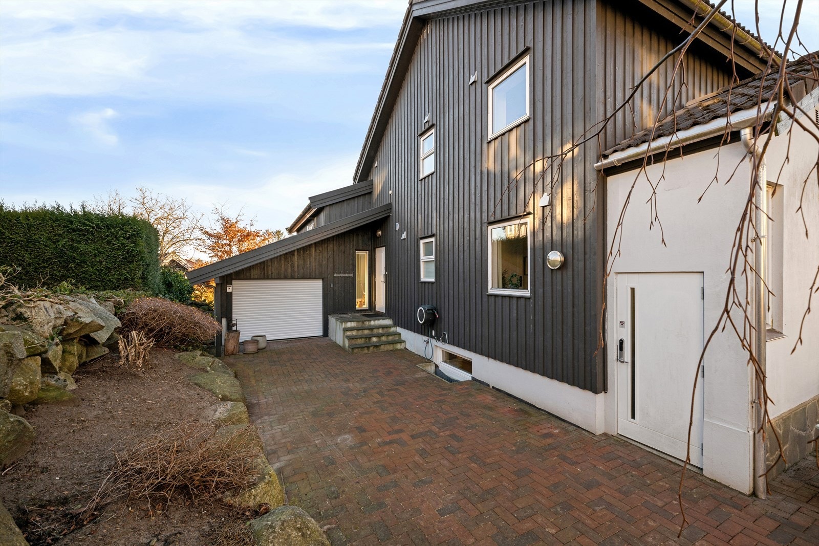 På baksiden av boligen er det garasje i dag benyttet som sykkelbod og lagring. Den har port på begge sider, slik at det er enkel tilkomst også fra hagen. Om ønskelig å bruke til bil, må natursteinskant i innkjørsel flyttes. Galleribilde