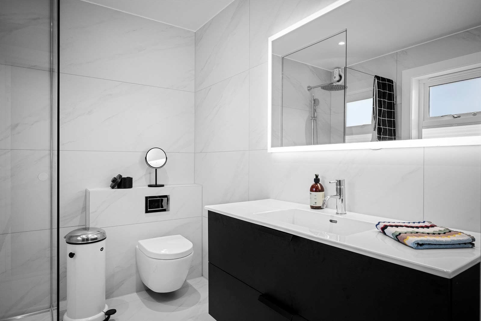 Delikat og moderne baderom med vannfallsdusj og håndholdt, stor seksjon og speil med lys. Vindu for naturlig lys. Håndkleholder. Galleribilde