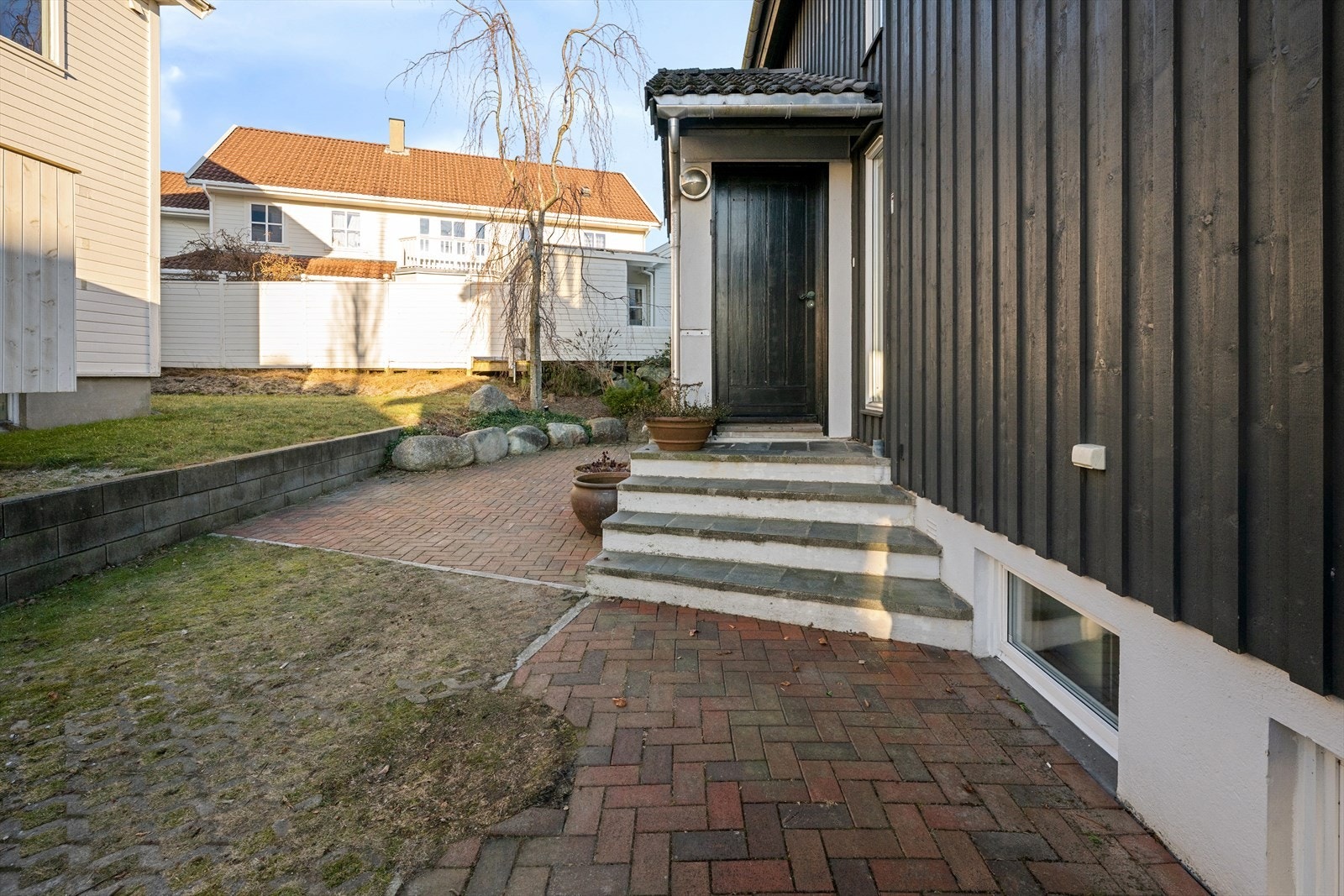 Elbil lader på vegg ved inngang. Takoverbygget inngangsparti. Videre passasje til bakgang/bi-inngang kjeller, samt garasje med port for god lagring. Galleribilde