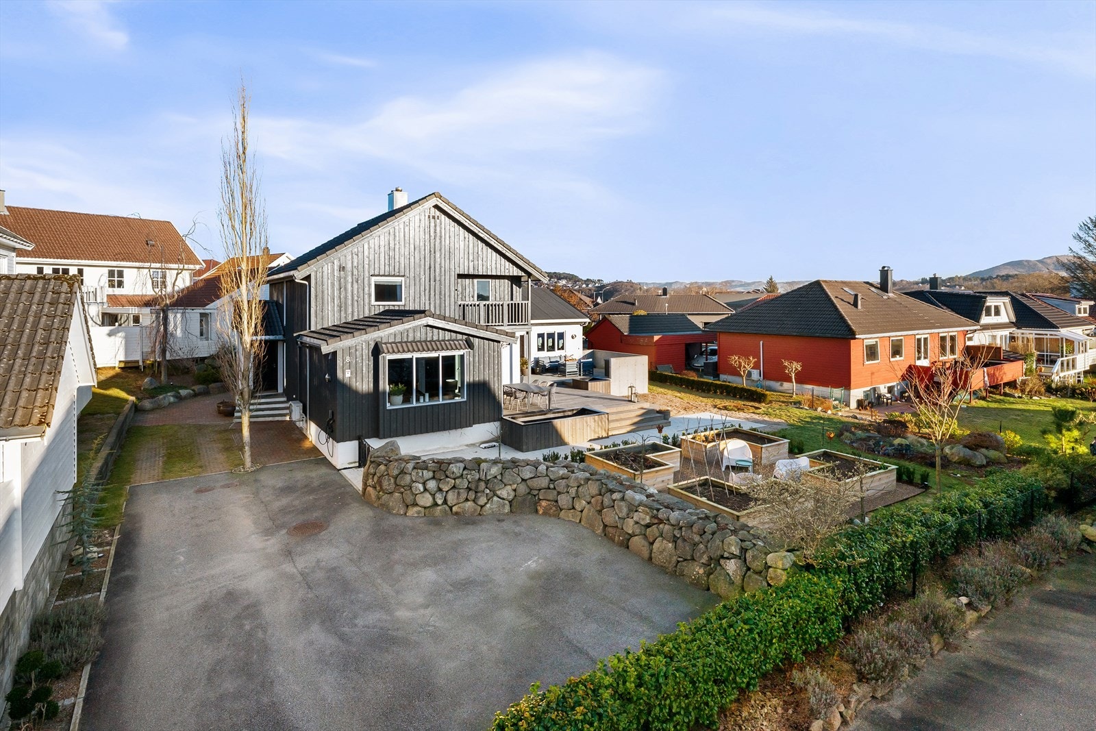 Romslig, asfaltert gårdsrom, samt belegningsstein med gressmønster for parkering av flere biler. Natursteinsmur og lekker stålport inn til påkostet hage. Galleribilde