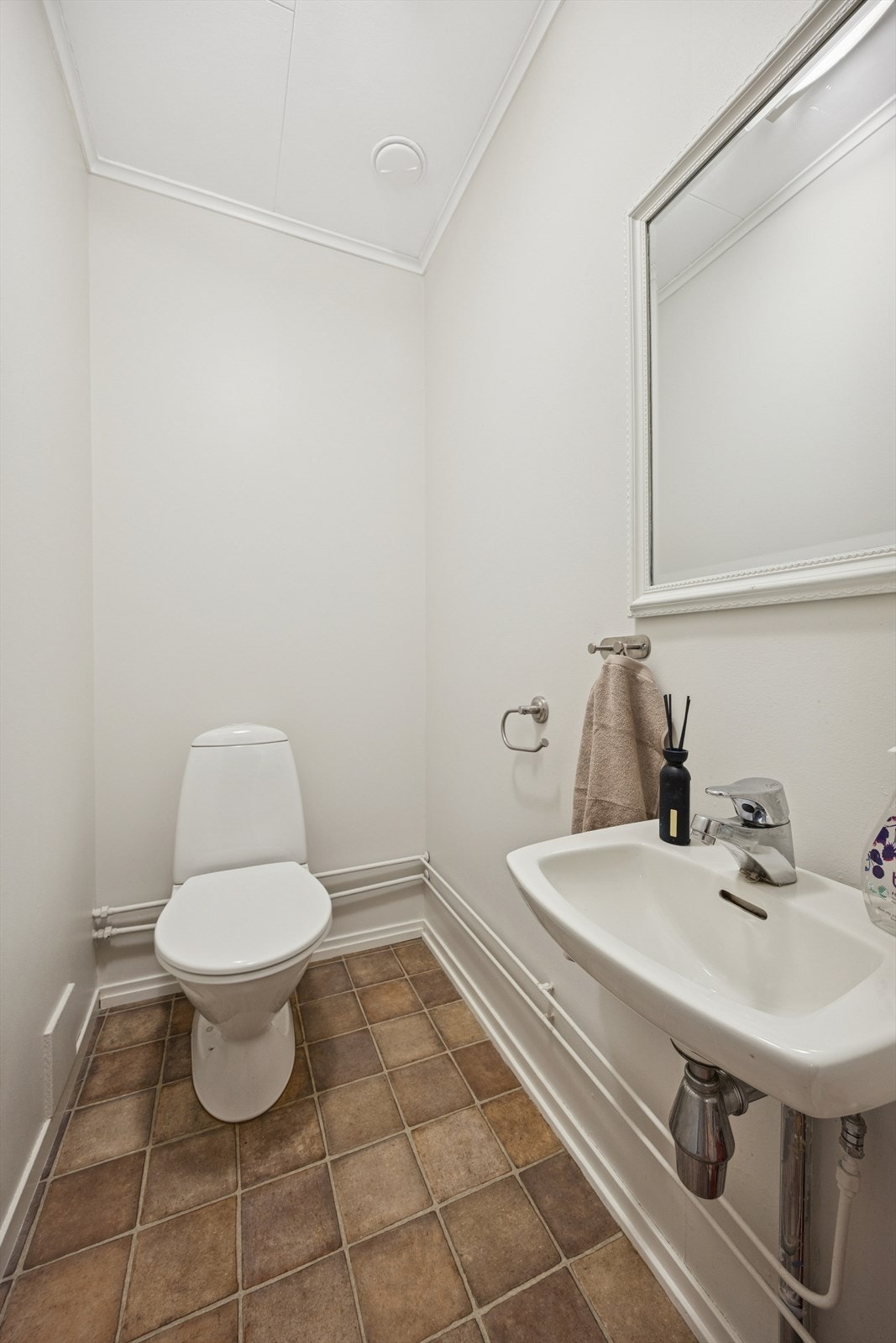 Toalettrommet er utstyrt med et gulvmontert toalett og en vegghengt servant. Galleribilde