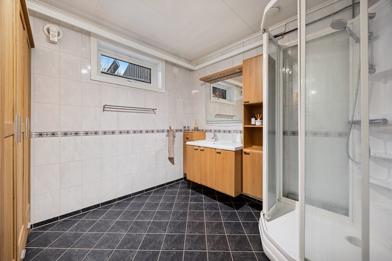 Baderomsinnredningen består av en servant nedfelt i baderomsinnredning, samt et dusjkabinett. Galleribilde