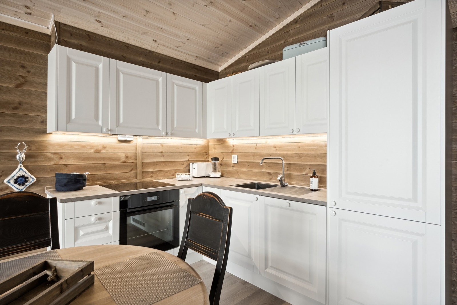 Kjøkkeninnredning med folierte skrog og malte og profilerte fronter. Laminat benkeplate og integrerte hvitevarer. Galleribilde