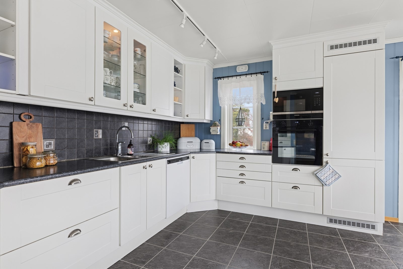 Kjøkkenet har folierte skrog og fronter, benkeplate med høytrykkslaminert overflate, en kum av rustfritt stål og kjøkkenventilator med avtrekk ut. Galleribilde