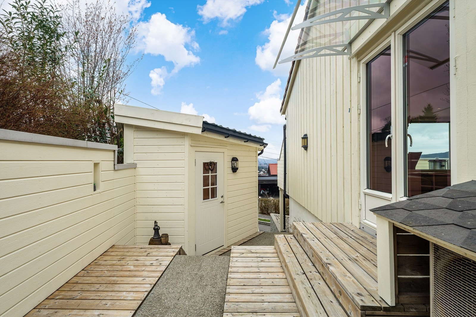 Fra stuen er det utgang til terrasse og gangvei til inngangsparti. Uthuset på bildet blir i dag brukt som kontor Galleribilde