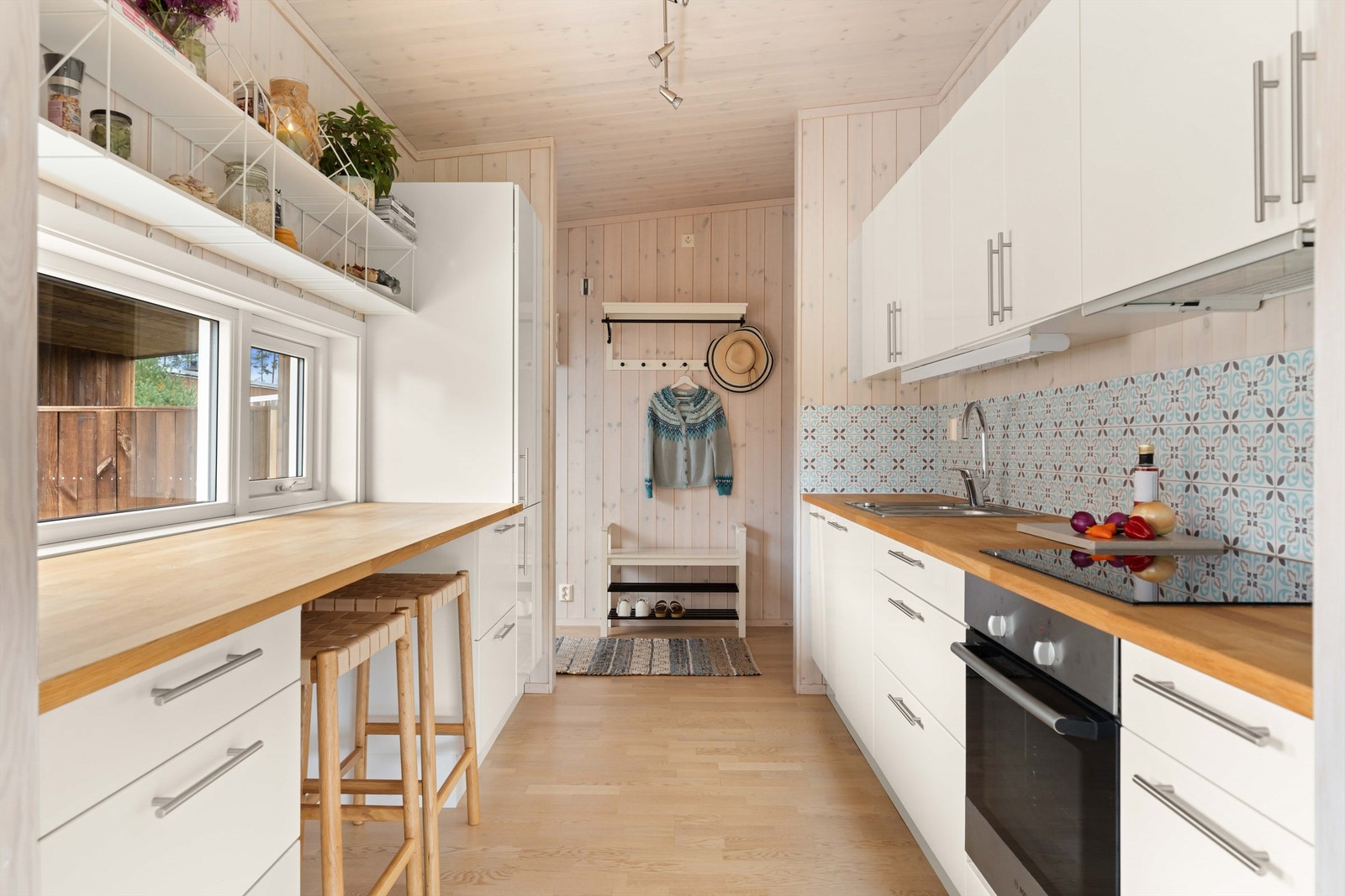 Kjøkkeninnredning av slette fronter i hvitt og benkeplate i tre som gir et tidløst uttrykk. Praktisk belysning og stikkontakter under overskap gir en funksjonell arbeidsflate. Galleribilde