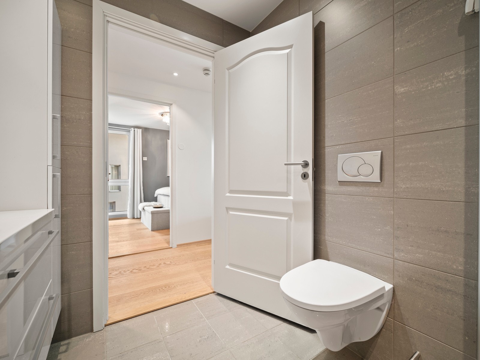 Innredningen består av nedfelt servant i en romslig baderomsbenk, veggmontert toalett og dusjhjørne med glassvegger. Galleribilde