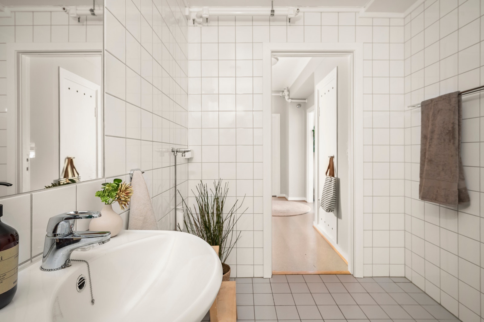 Stort, flislagt bad i lyse, moderne farger med opplegg for vaskemaskin, praktisk baderomsinnredning og dusjhjørne med glassdører. Galleribilde