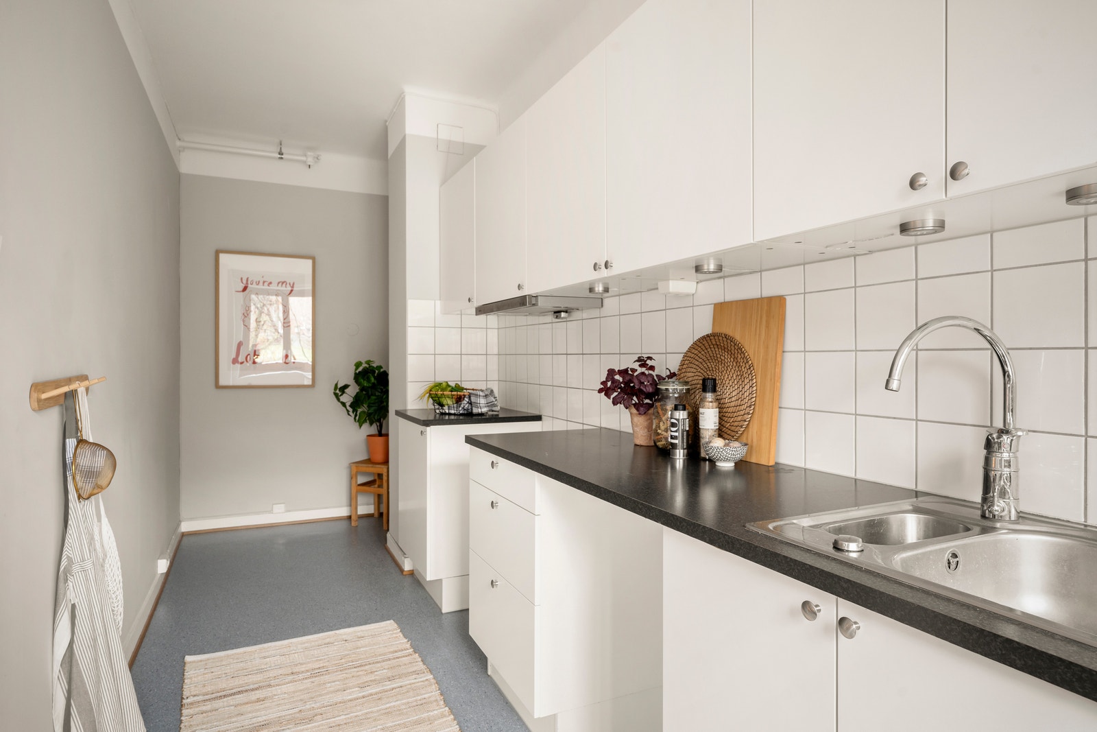 Kjøkken fra HTH i lyse, moderne farger, med opplegg for oppvaskmaskin, benkbelysning og plass til spisegruppe. Galleribilde