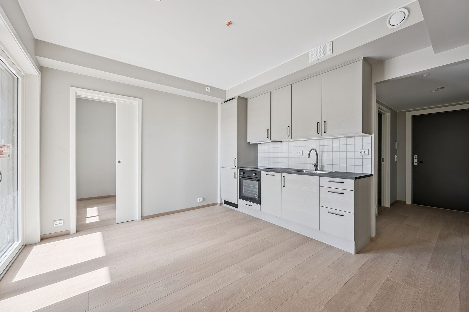 Stue og kjøkken i åpen løsning. Kjøkkenet har integrerte hvitevarer Galleribilde