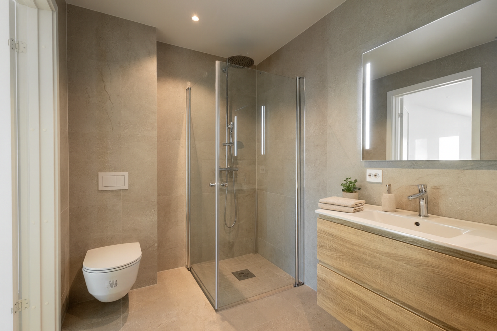 Lekkert bad med smakfulle materialer og moderne funksjonalitet. Badet er innredet med servantinnredning, speil, opplegg til vaskemaskin og dusjhjørne. Galleribilde