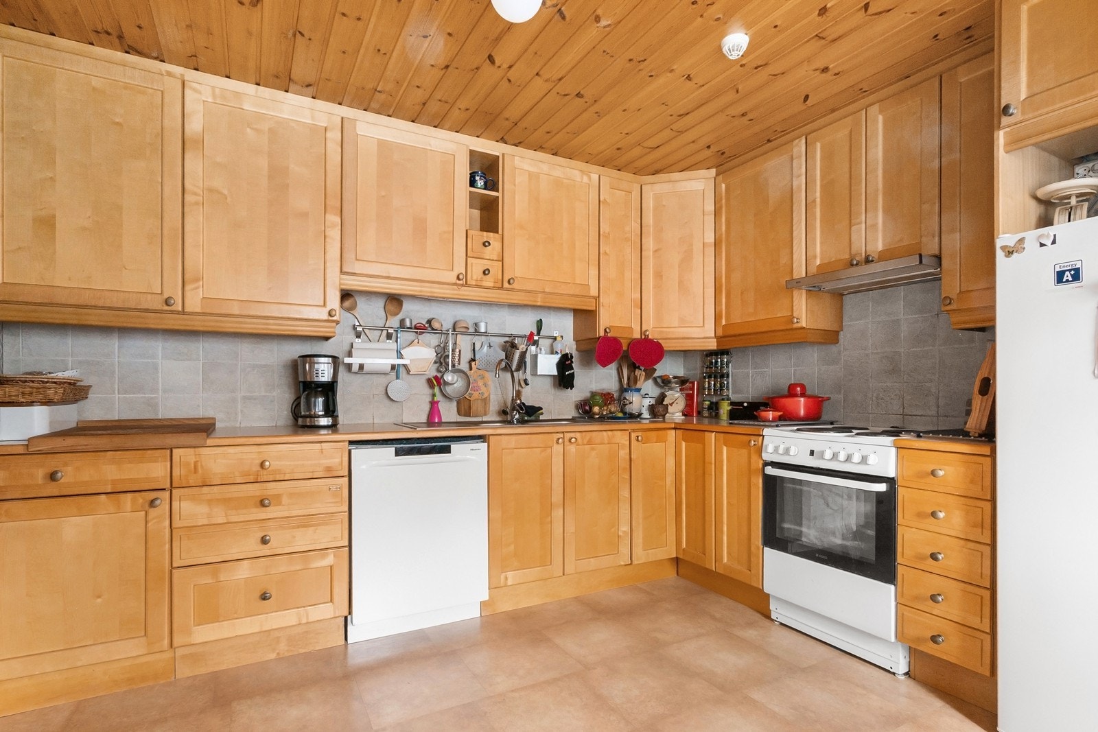 Innredningen har profilerte fronter, laminat benkeplate og fliser over benk. Frittstående hvitevarer består av komfyr, oppvaskmaskin og kjøleskap. Galleribilde