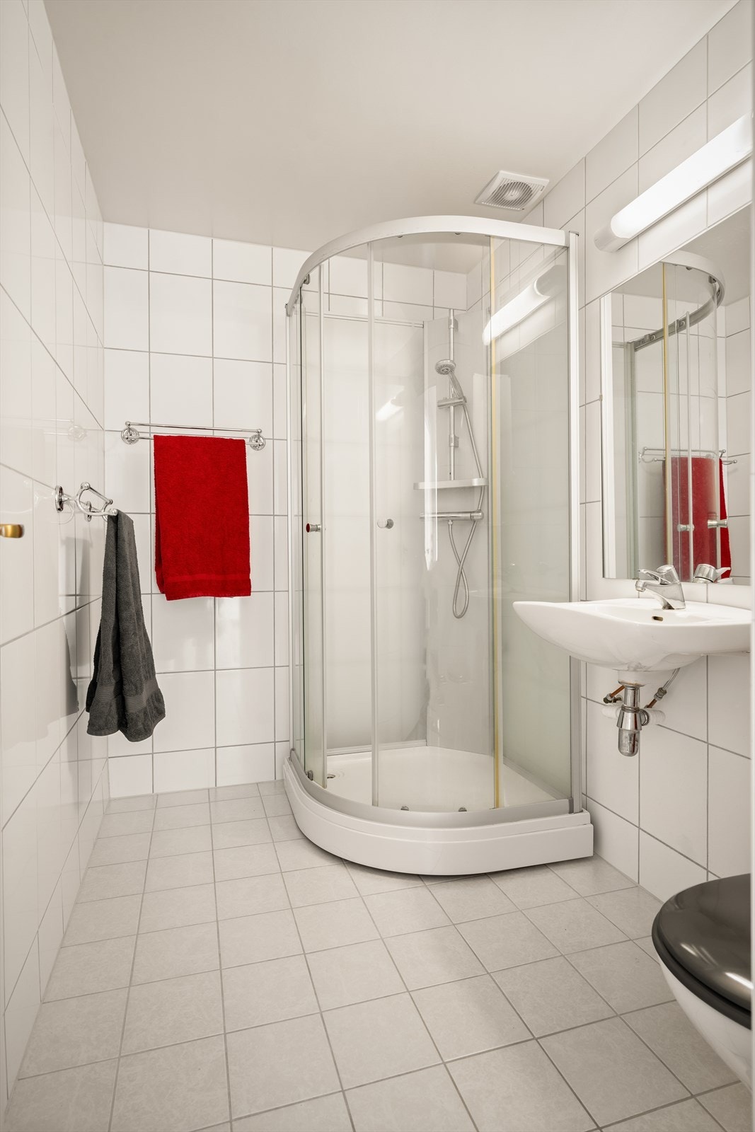 Boligens andre bad er flislagt og utstyrt med dusjkabinett, servant og toalett. Galleribilde